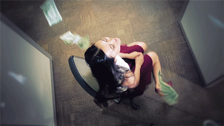 Gif of money raining down on a woman that is spinning in her chair