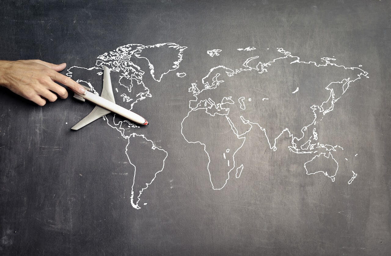 A world map drawn with chalk with a toy plane